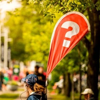 Event staff member holding a red flag with a question mark, ready to answer spectator questions at the National Bank Open tournament.