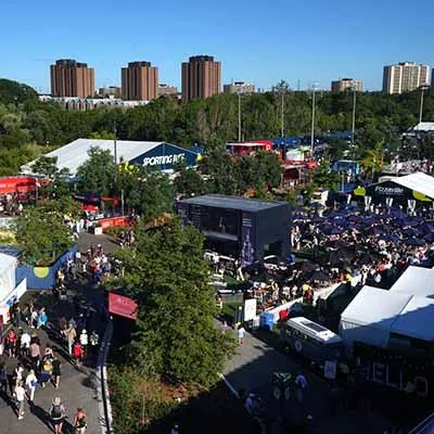 A bustling crowd at the National Bank Open tournament in Toronto, with fans enjoying activities and vendors in a lively outdoor area.